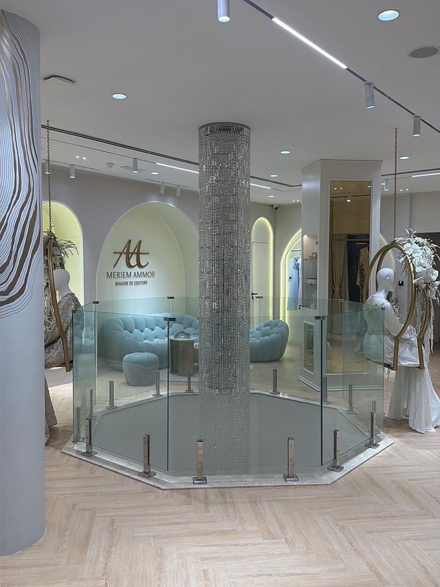 Salon de la boutique Meriem Ammor Maison de Couture à Jumeirah 1, Dubaï, avec lustre en cristal et logo doré